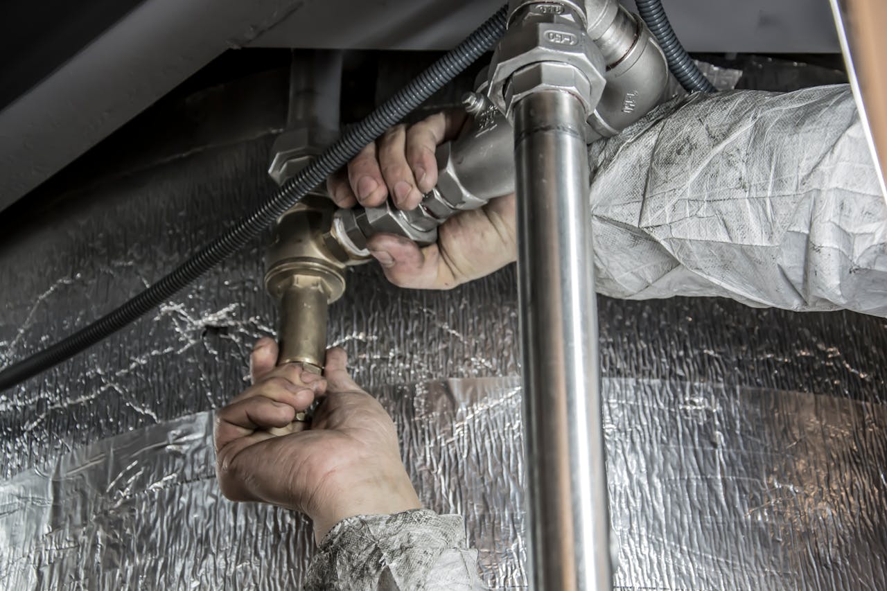 who-we-are Close-up of a plumber's hands installing steel pipes indoors, showcasing skilled manual work.